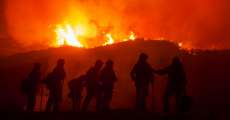 Firefighters silhouetted against flames.