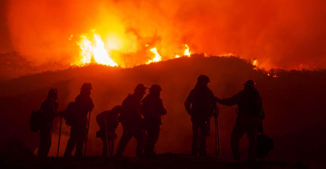Firefighters silhouetted against flames.
