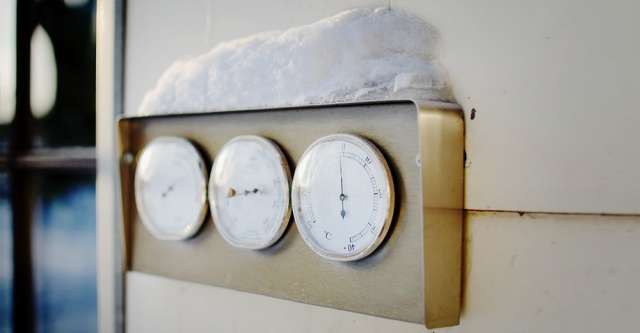 Cold temperatures and snow on thermometer.