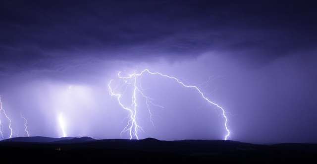 Lightning striking the ground at night.