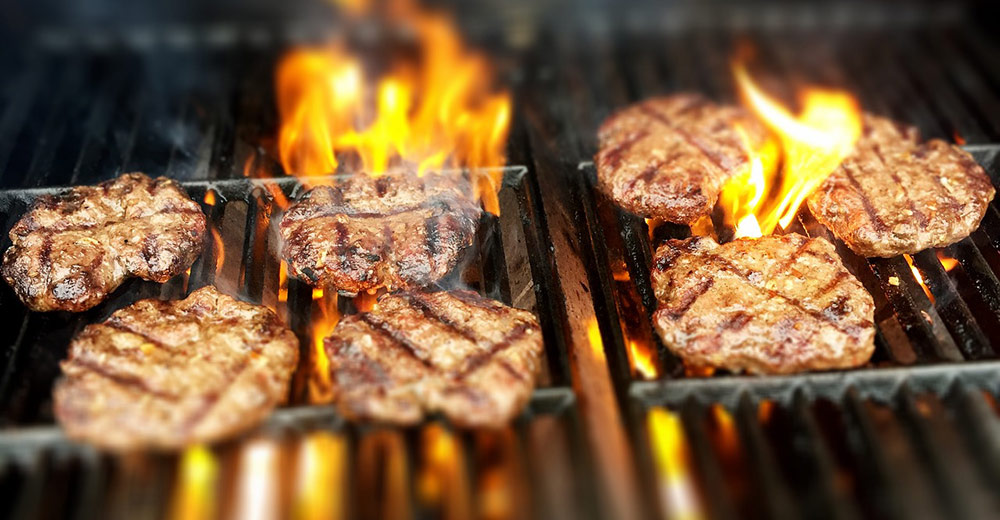 Burgers on a flaming grill.