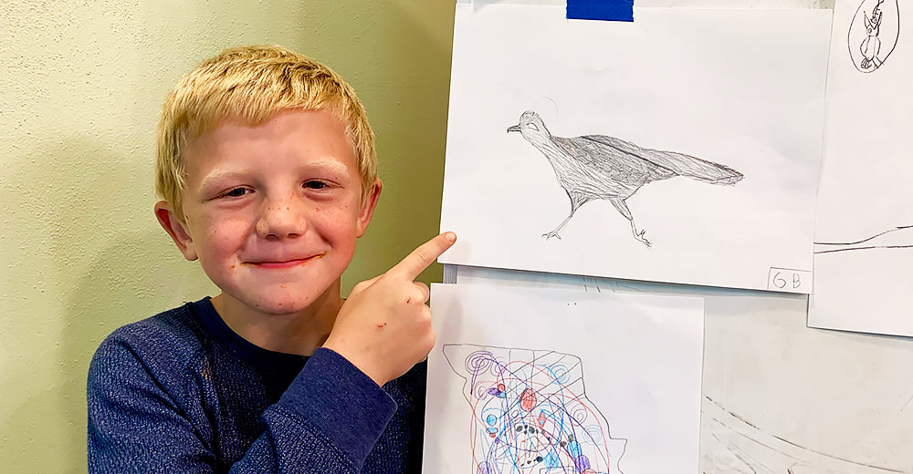 3rd grader Gideon Biring shows off his artwork