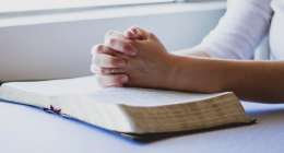 hands praying over an open Bible