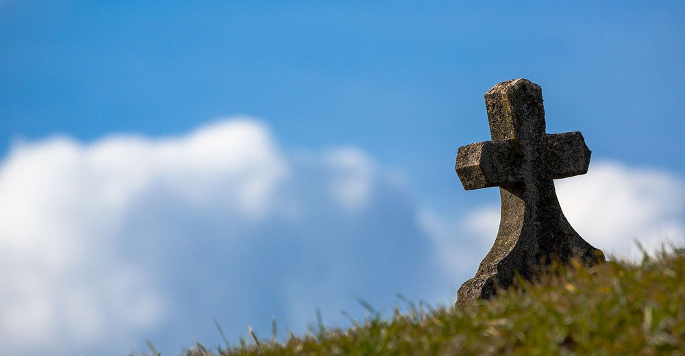 A graves tombstone on a hillside.