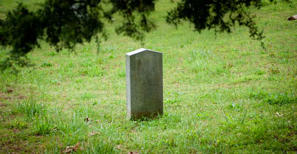 Tombstone inside of a grassy graveyard