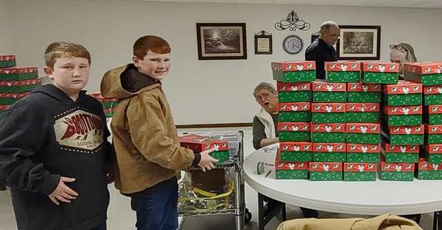 Kids helping pack Christmas shoe boxes.