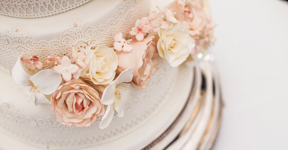 A white wedding cake with flowers on the side.