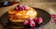 A stack of pancakes withA stack of pancakes with syrup and raspberries on top. syrip and rasberries on top.