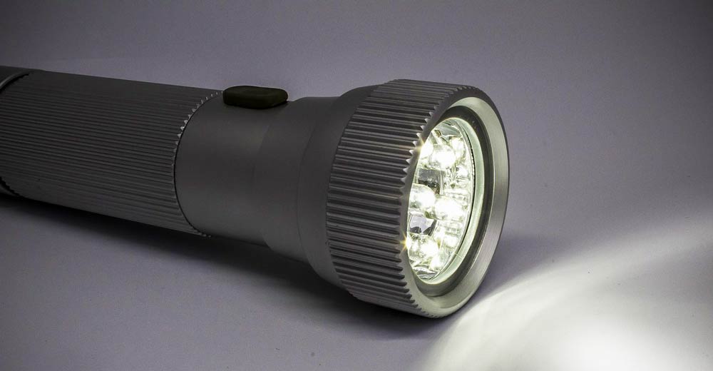 A silver metal flashlight in the dark.