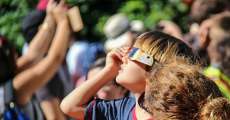 Kid looking at eclipse through glasses.