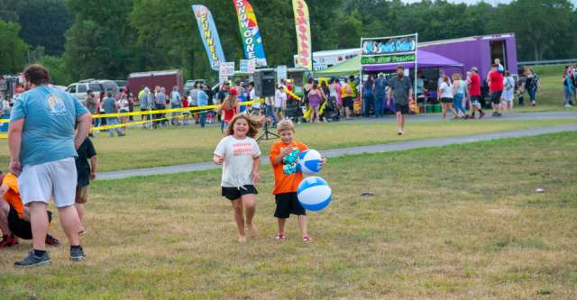 Two kids playing with Shelter Insurance beach balls at the Alton Independence Day celebration on July 3, 2023.