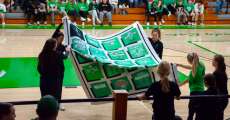 Some Lady Bobcats players holding up a handmade Bobcats quilt on December 1, 2023.