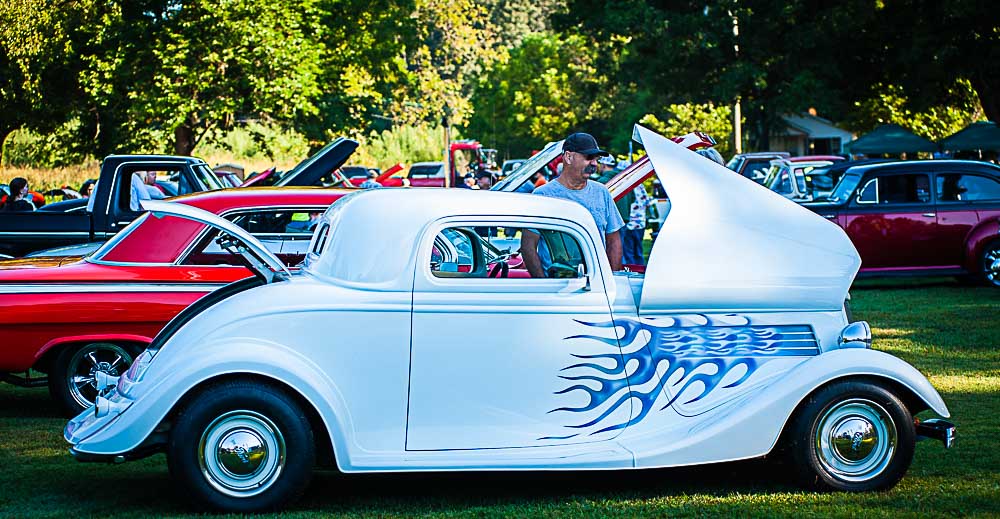 A classic car with its hood open at the car show.