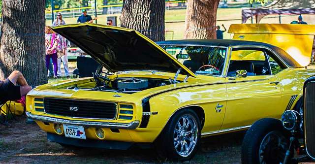A yellow Camero sitting beside some other classic cars.