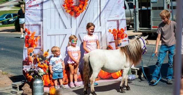Three kids getting a picture with a miniature pony.