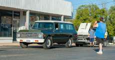 A classic dark green car being admired on the square at the cruise-in.