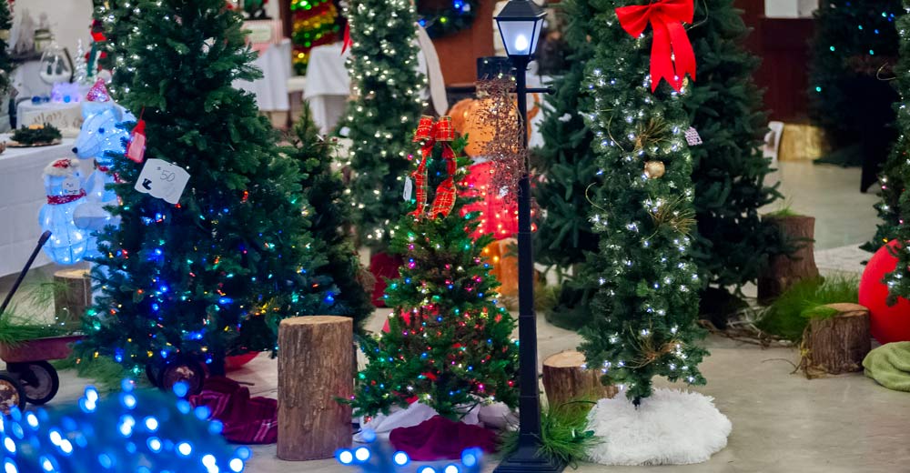 A variety of artificial Christmas trees sitting on the floor.