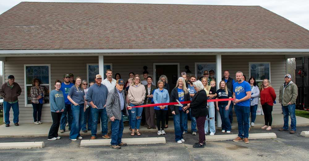 Individuals and representatives for various businesses pose for the ribbon cutting at United Country.