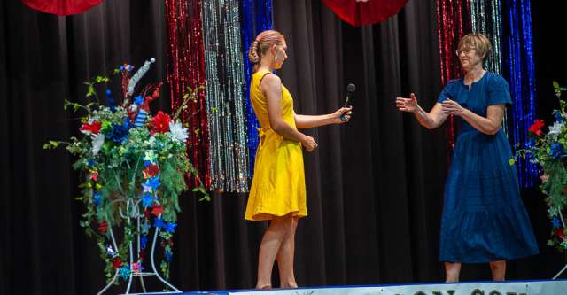 A young lady trying to win the Miss Liberty Bell title hands the mic to the emcee after talking to the audience.