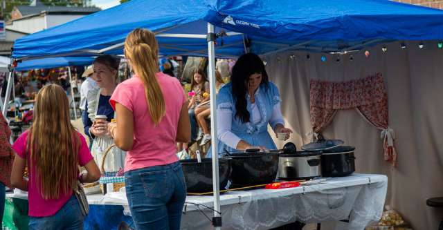 A lady with the Oregon County Historical Society dishing out baked beans to festival attendees.